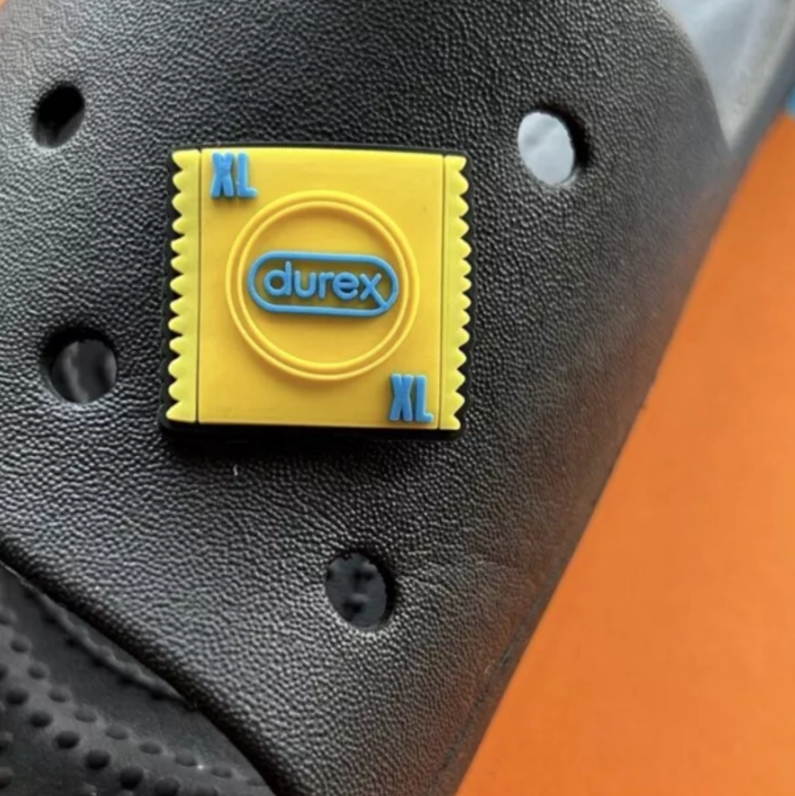 Yellow XL Condom croc like shoe charm. Shown on a black croc shoe. 