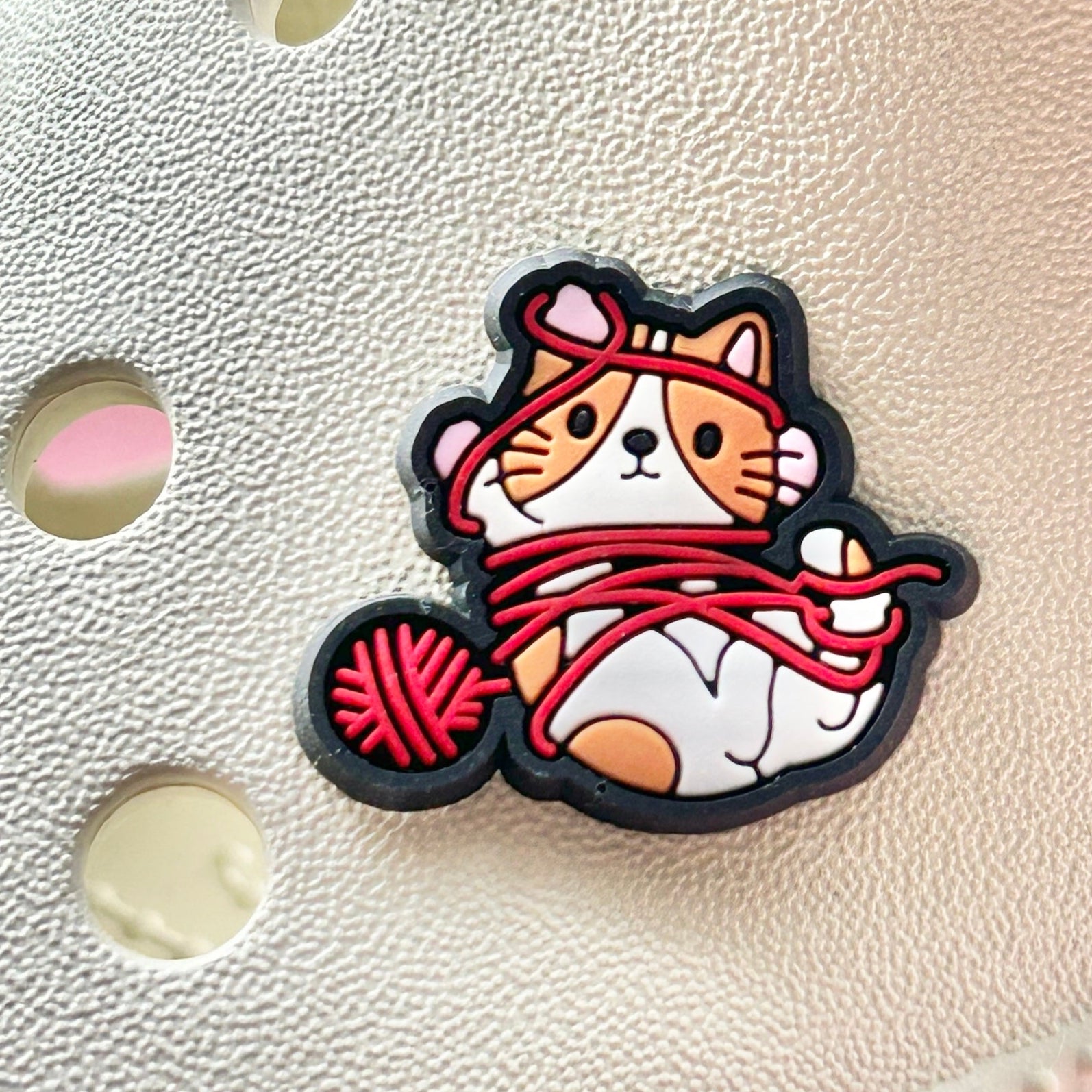 Cat with a Ball of Wool croc like shoe charm. Shown on a cream croc shoe. 