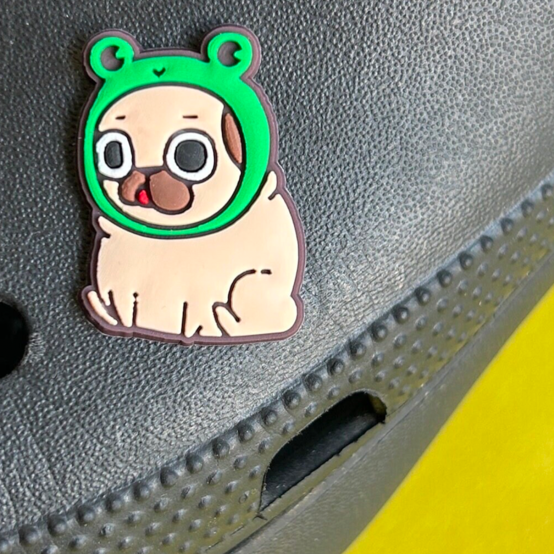 Pug Dog wearing a Frog Hat croc like shoe charm. Shown on a black croc shoe. 