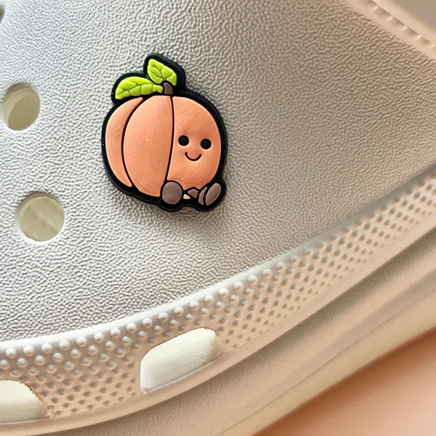 Peach croc like shoe charm. Shown on a cream croc shoe. 