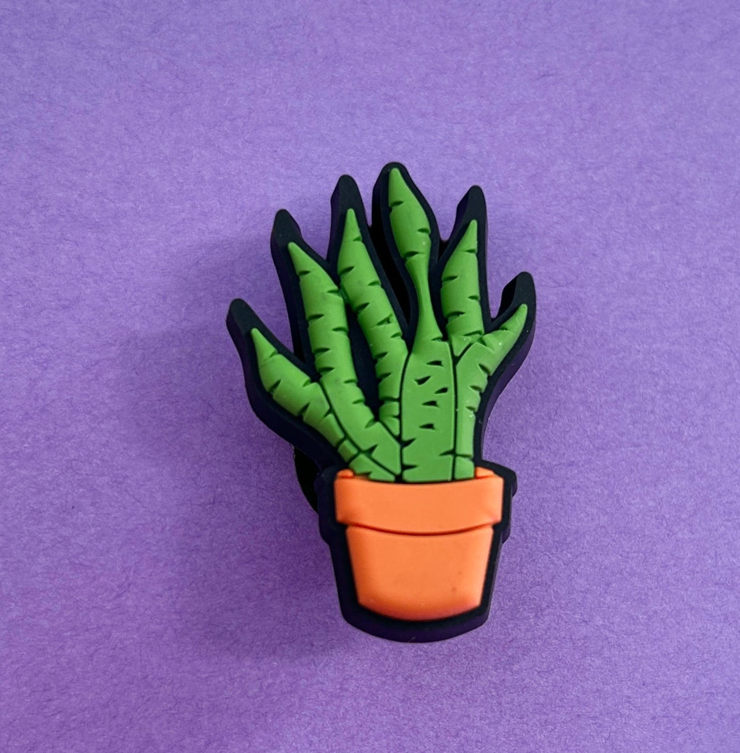 Snake plant croc shoe charm. Green plant in an orange plant pot. 