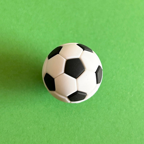 3D White and Black football croc shoe charm. Sport. Top down view on a green background. 