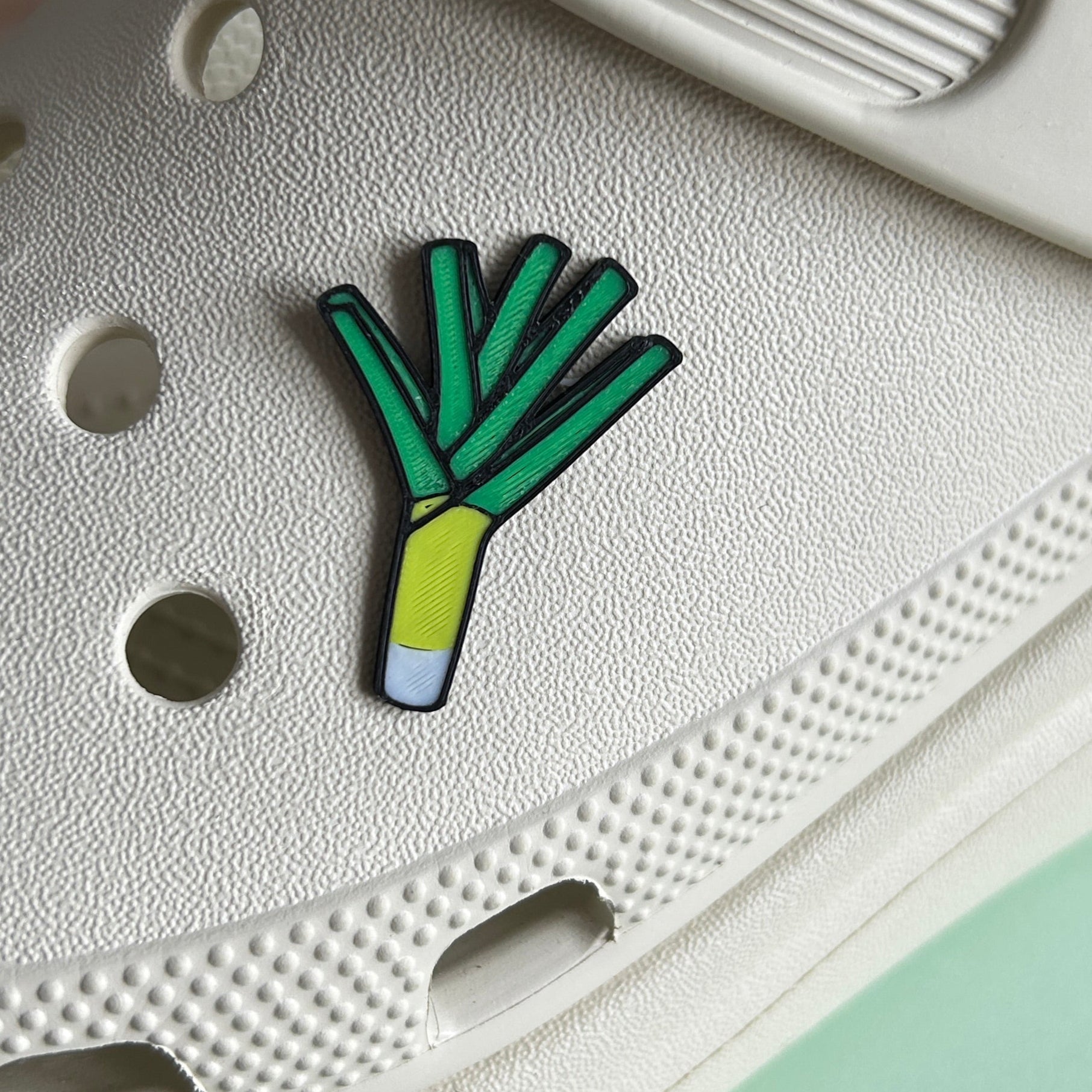 3D printed handmade Leek Vegetable. Green charm. PLA plastic. Shown on a cream croc shoe. 