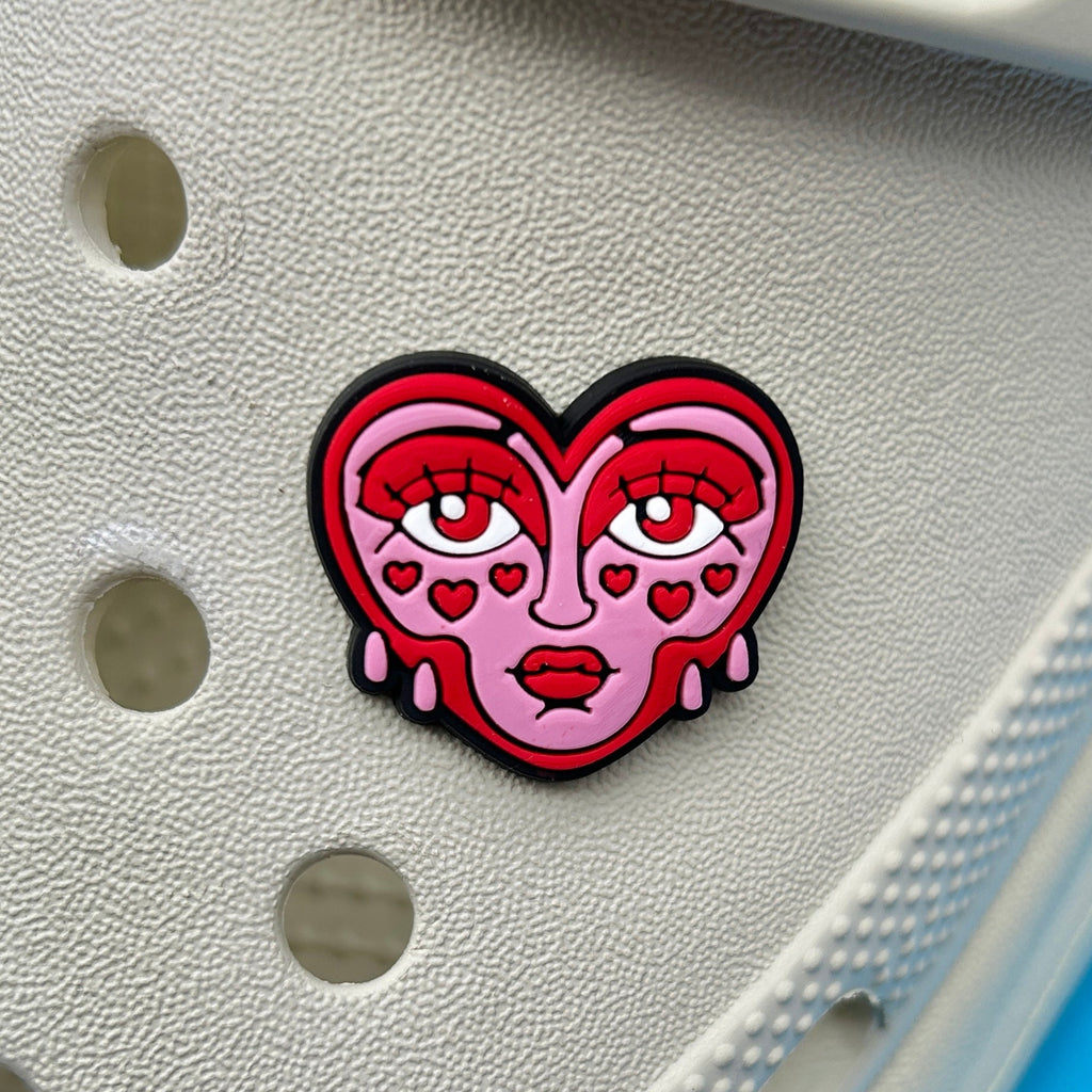 Cute crying face heart shoe charm attached to white clog.