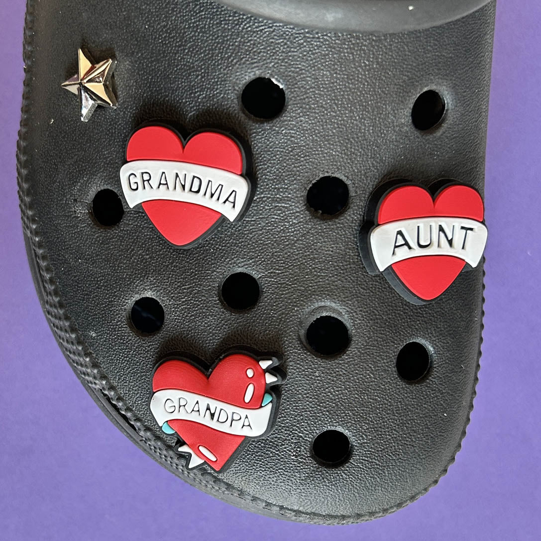 Three heart croc charms with the words Grandma, Aunt and Grandpa. 