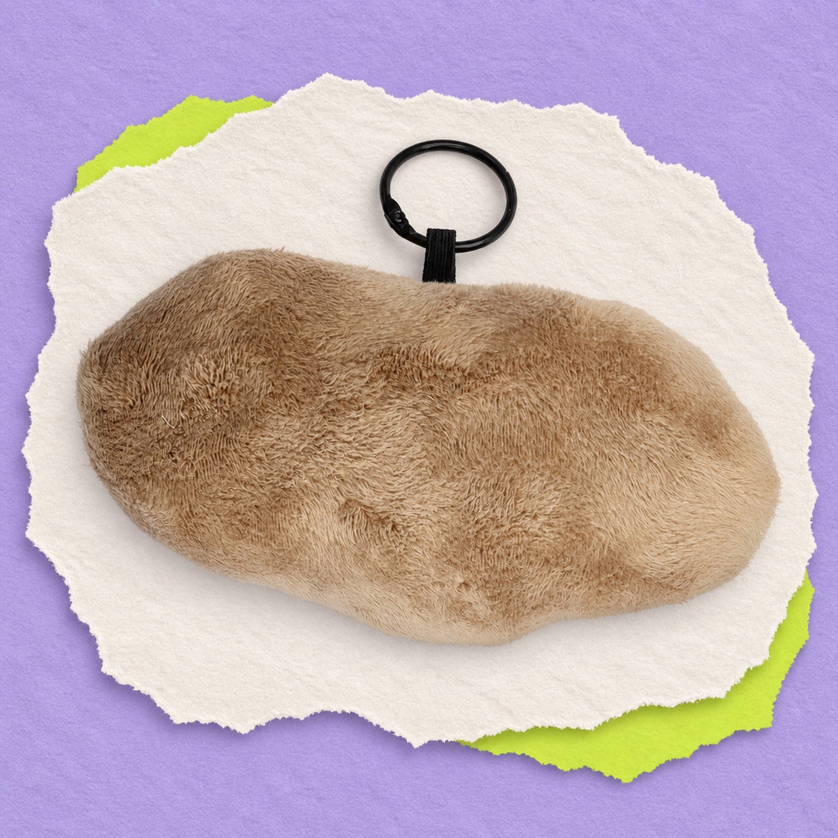Back view of ET bag charm light tan-brown color, featuring a black plastic key ring, presented on a stylized torn-paper graphic over a solid purple background.