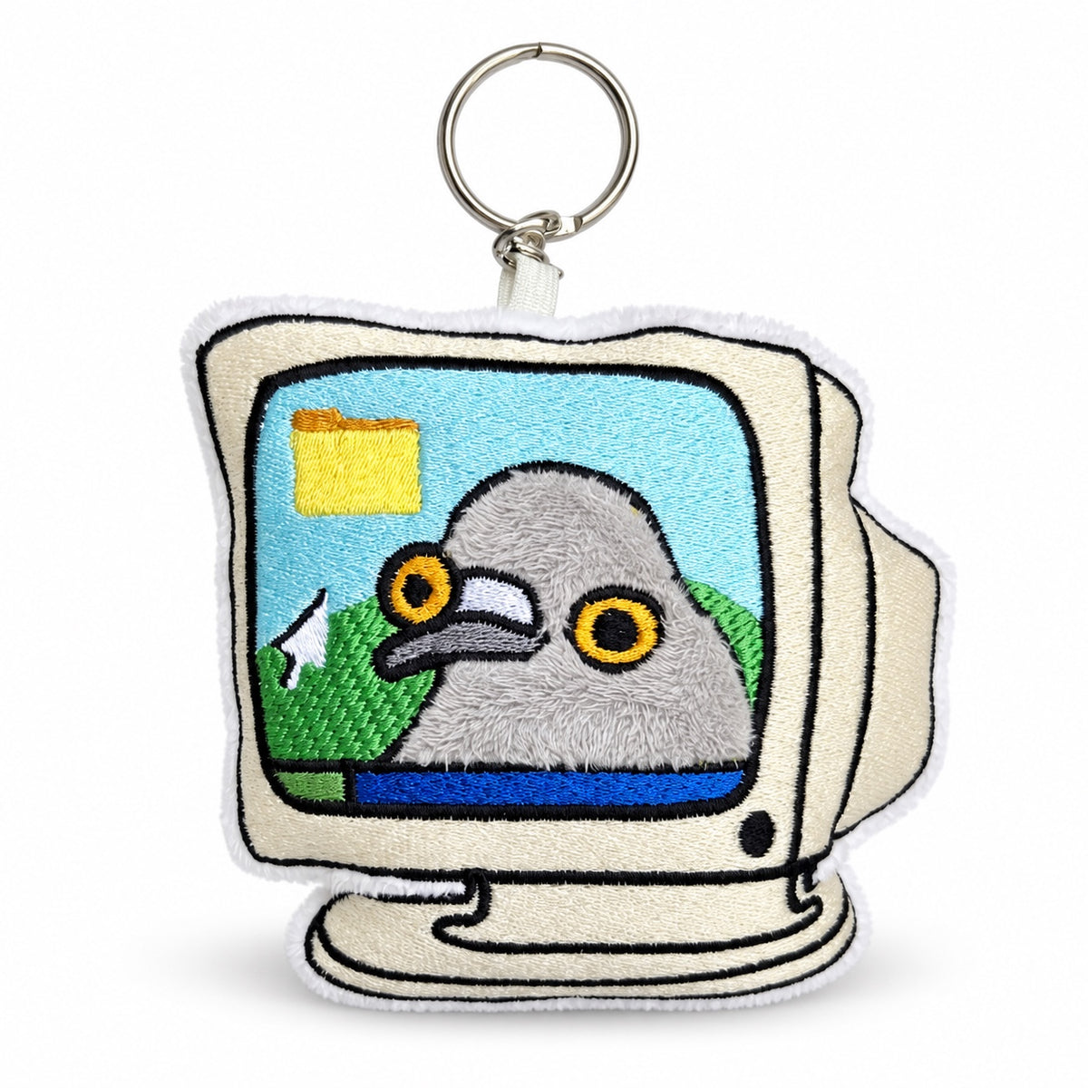 An embroidered keychain shaped like a retro computer monitor, featuring a gray pigeon with yellow eyes on a light blue screen background. The keychain has a white embroidered border, a silver metal split ring, and is shown on a clean white background.