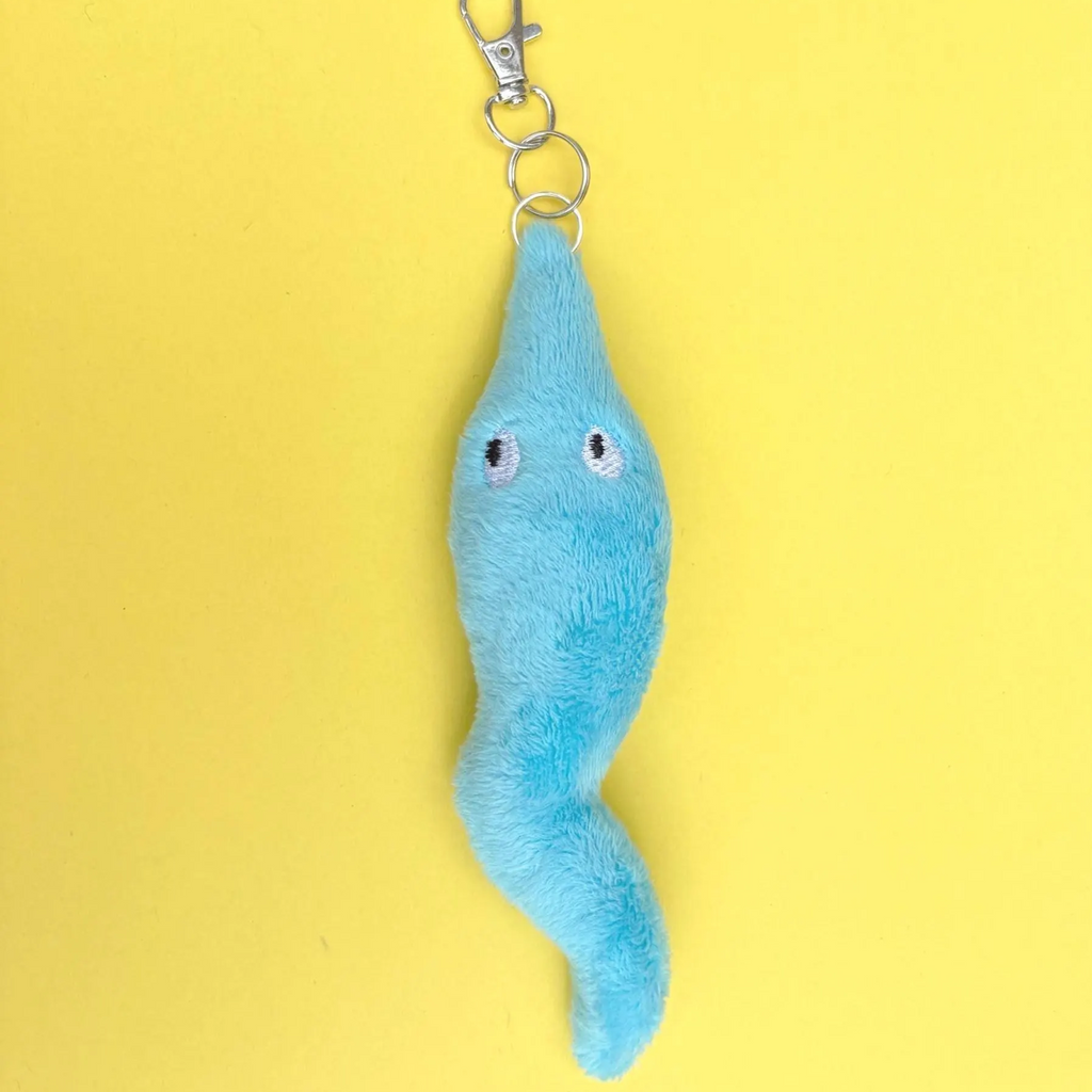 A light blue plush worm keychain with embroidered eyes and a silver metal clasp, set against a solid yellow background.