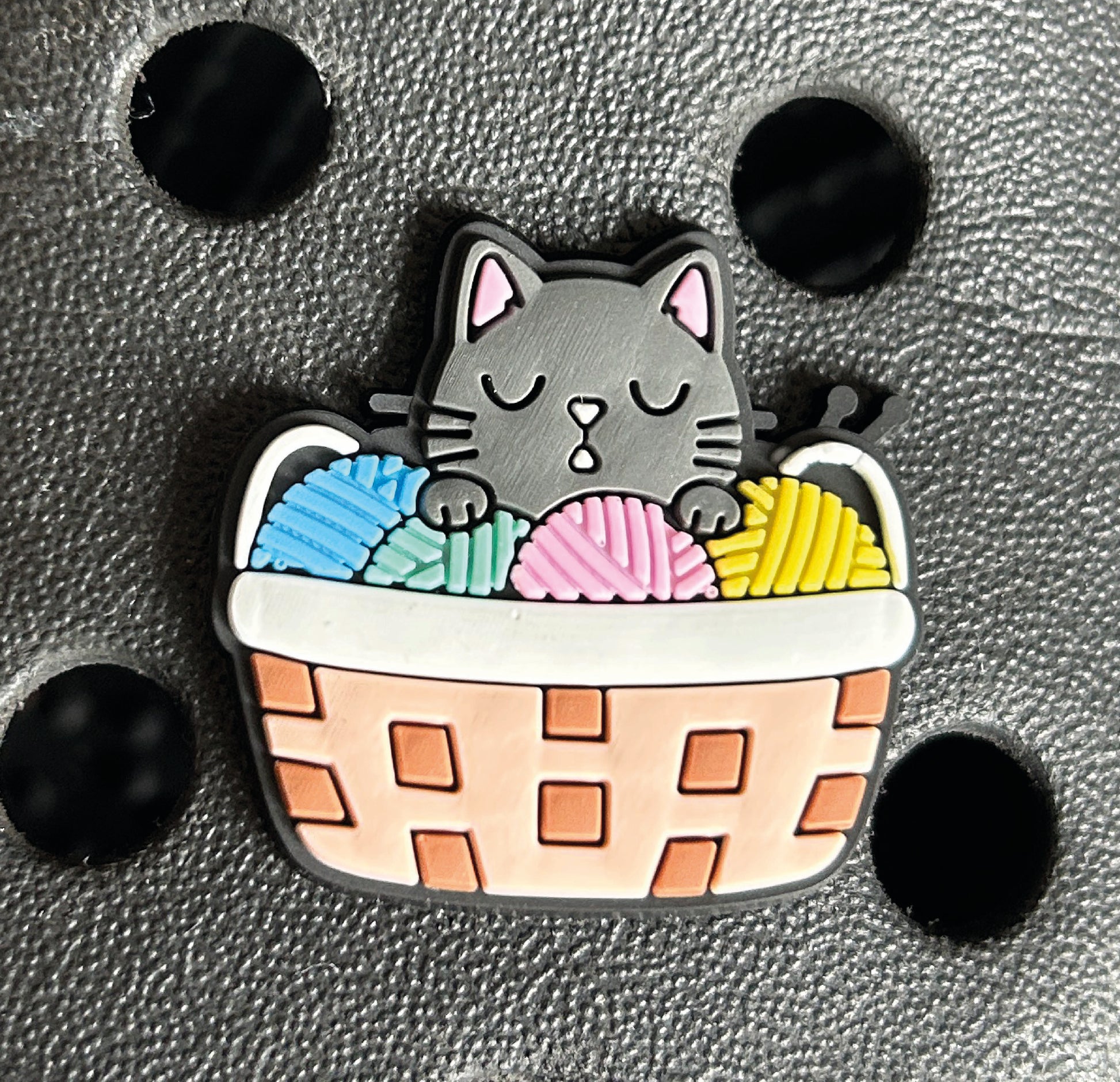 Black cat in a basket of wool croc like shoe charm. 